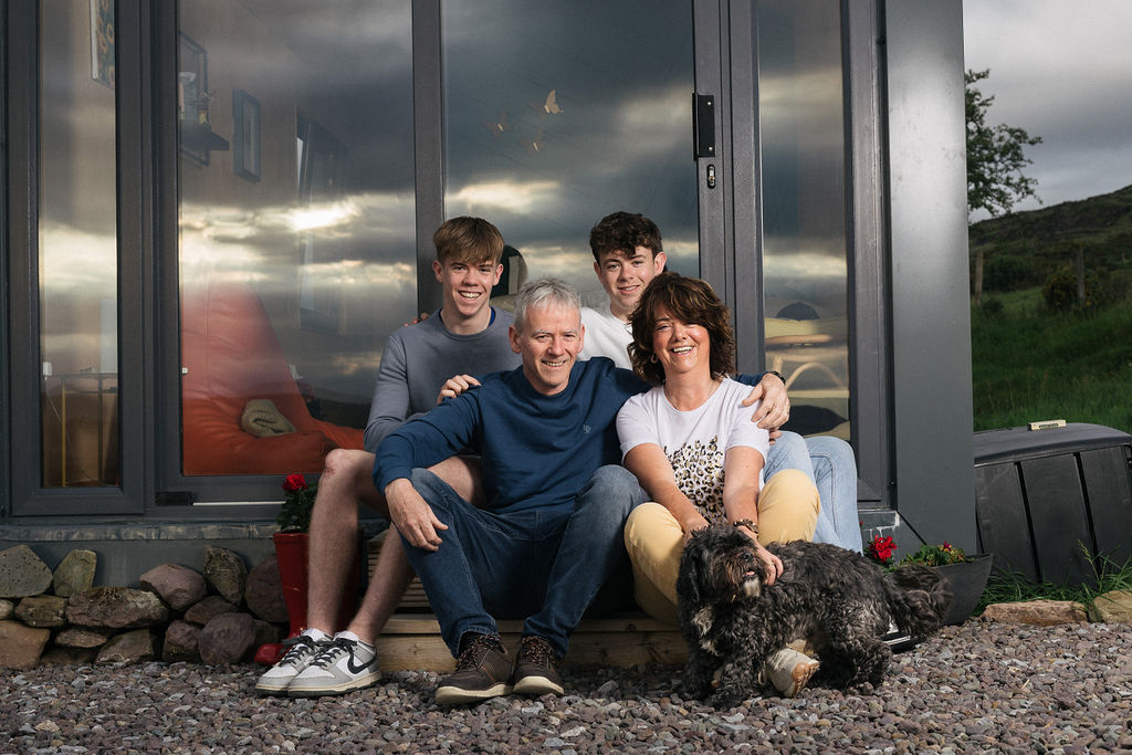 Declan and Catriona Brown with their two sons and their dog sitting outside a glamping cabin
