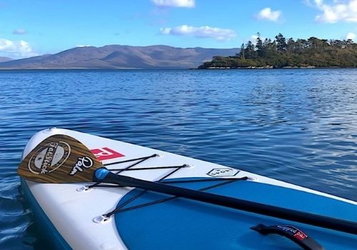 Paddleboard on the calm water of Kenmare Bay with mountains behind