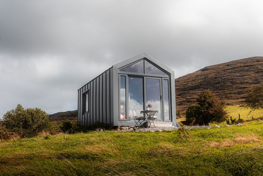 Saileach cabin exterior on a grassy hillside below the mountain