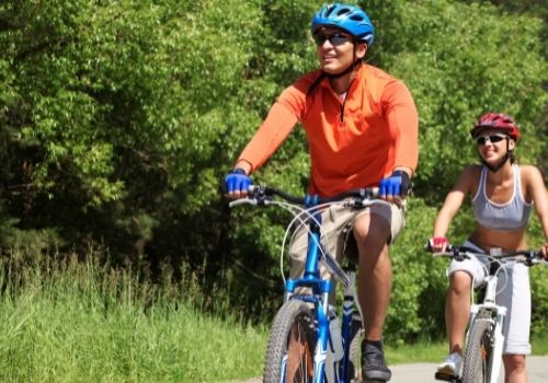Two cyclists riding along a quiet tree-lined road