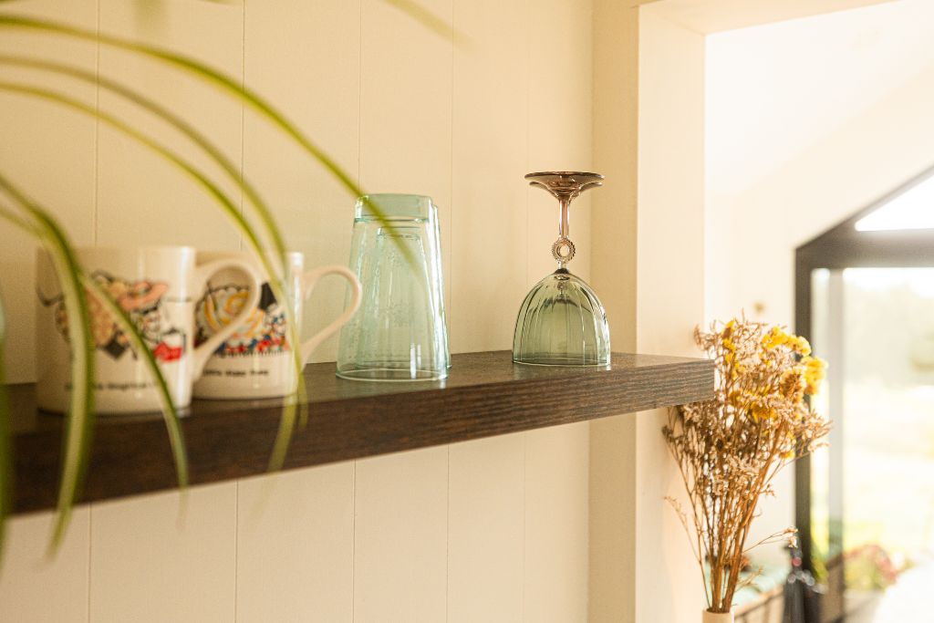 Dark timber shelf with glassware and mugs in soft afternoon light