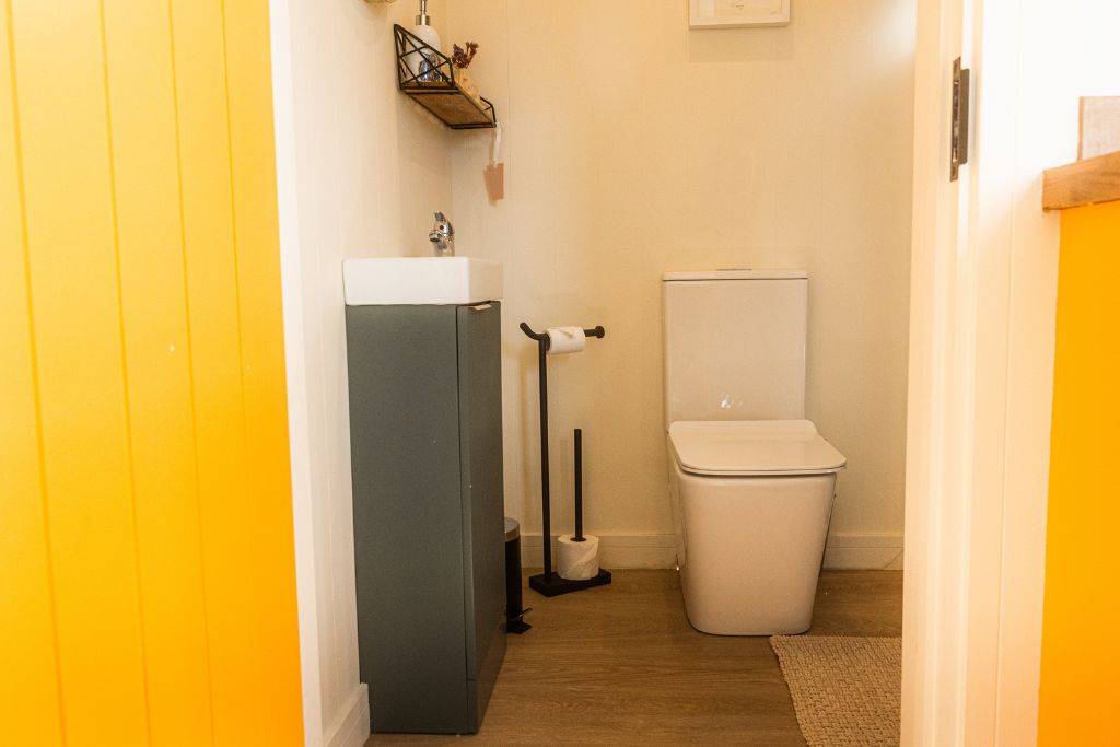 Cabin bathroom with a compact grey vanity unit and a yellow panelled door