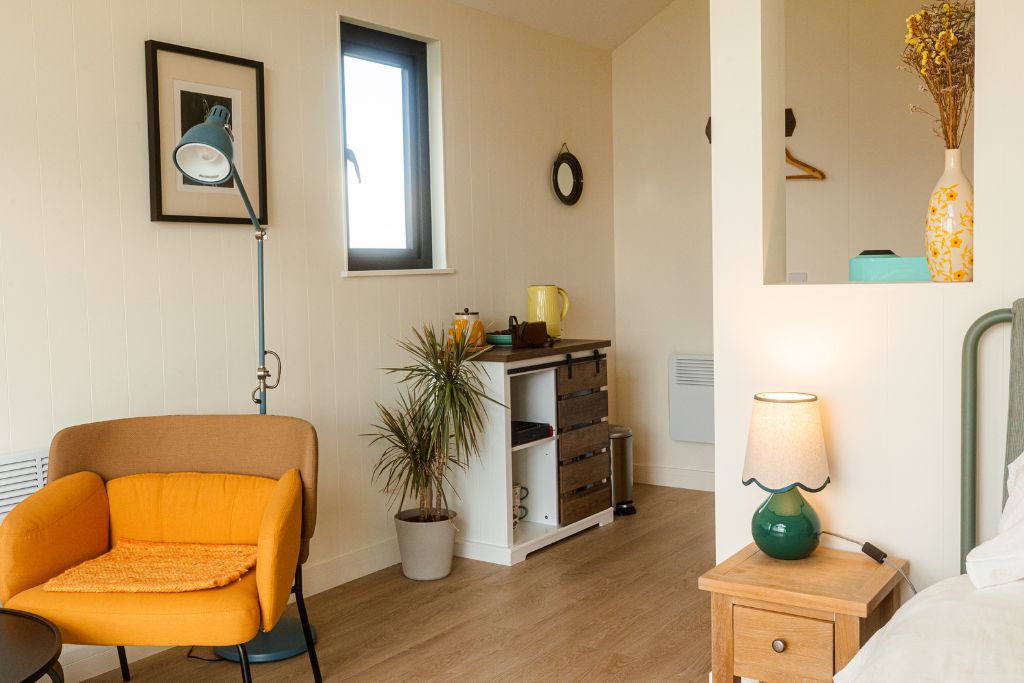 Cabin corner with an orange armchair, reading lamp and a potted plant