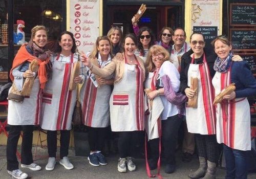 A food tour group in aprons holding bread outside a Kenmare bakery